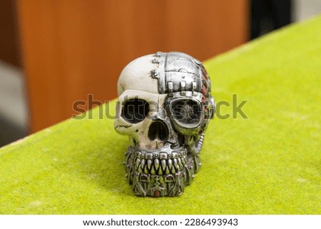 Plastic toy human skull with iron elements of a robot on the green background