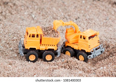 Plastic Toy Orange Color For Construction. By Loading And Digging And Dump Truck On Soil Ground.