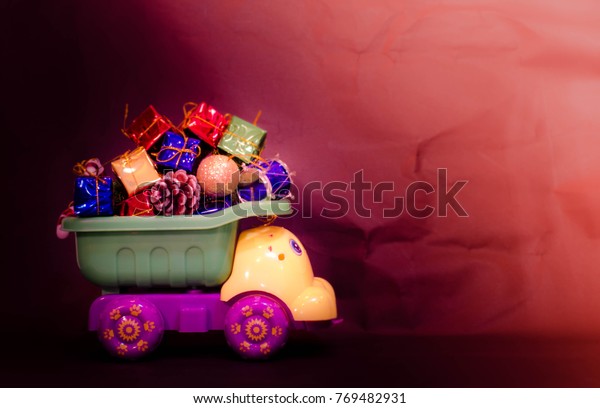 plastic toy truck load stuff and present gift\
boxes on its tray with dark\
background