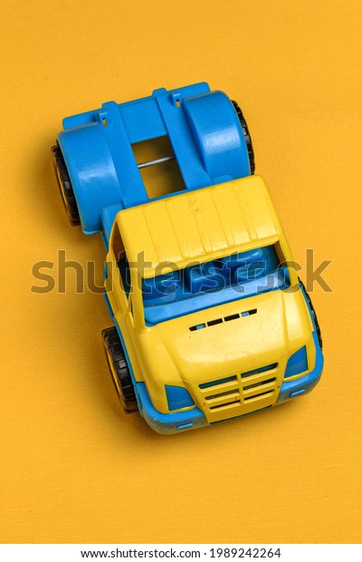Plastic toy truck\
on yellow background\
close-up