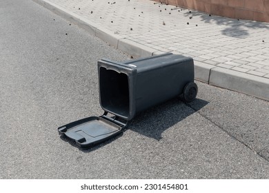 Plastic trash can container fell fallen on ground road