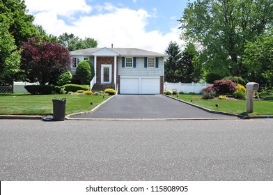 Plastic Trash Container on curb at driveway end of high ranch suburban home in residential neighborhood