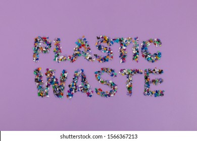 Plastic Waste Text Consisting Of Small Plastic Pellets Collected From The Sea Water. Rethinking The Environment By Reducing Or Reusing Plastics. Circular Economy Concept. Lilac Purple Background