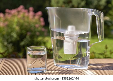 Plastic Water Filtration Pitcher And A Clean Glass Of A Clear Water On The Summer Garden Background In Sunny Warm Summer Day In Countryside