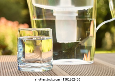 Plastic Water Filtration Pitcher And A Clean Glass Of A Clear Water On The Summer Garden Background In Sunny Warm Summer Day In Countryside