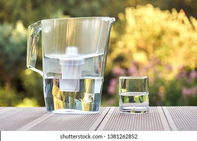 Plastic Water Filtration Pitcher And A Clean Glass Of A Clear Water On The Summer Garden Background In Sunny Warm Summer Evening In Countryside