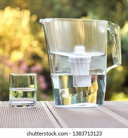 Plastic Water Filtration Pitcher And A Clean Glass Of A Clear Water On The Summer Garden Background In Sunny Warm Summer Evening In Countryside