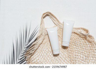 Plastic White Tubes For Cream Or Lotion And Cloth Shopping Bag. Sunscreen Cosmetic On White Background With Shadows From Palm Leaves. Beauty Summer Concept For Face Care