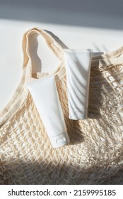 Plastic White Tubes For Cream Or Lotion And Cloth Shopping Bag. Sunscreen Cosmetic On White Background With Shadows From Palm Leaves. Beauty Summer Concept For Face Care