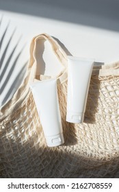 Plastic White Tubes For Cream Or Lotion And Cloth Shopping Bag. Sunscreen Cosmetic On White Background With Shadows From Palm Leaves. Beauty Summer Concept For Face Care