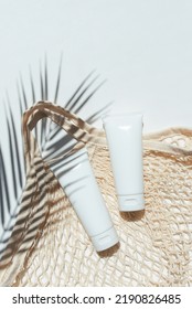 Plastic White Tubes For Cream Or Lotion And Cloth Shopping Bag. Sunscreen Cosmetic On White Background With Shadows From Palm Leaves. Beauty Summer Concept For Face Care