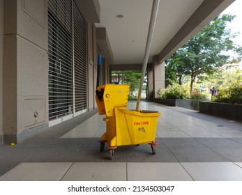 plastic yellow mop bucket and wringer trolley set. cleaning supplies. with the words achtung in 'german' and 'cuidado' in spanish which means attention