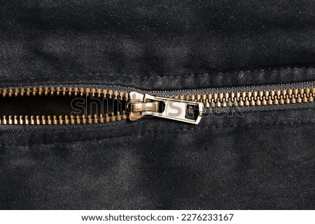 Plastic zipper background. Dark black coat zipper. Empty copy space fabric texture. Closeup zipper teeth. Metal shiny clothing part. Closeup zipped zipper.	