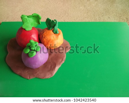 Plasticine clay fruit on green flute board. 