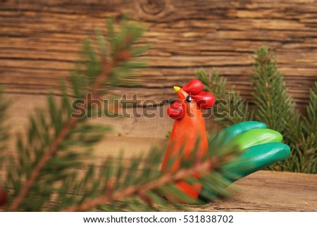 Plasticine Merry Christmas Rooster on  background  old board and fir branches.
Symbol 2017 - Fire Cock.