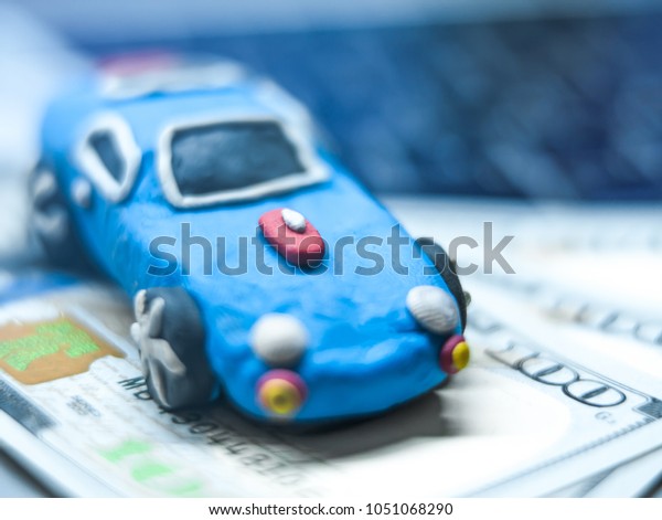Plasticine toy car with dollars is on the\
laptop. The\
programmer