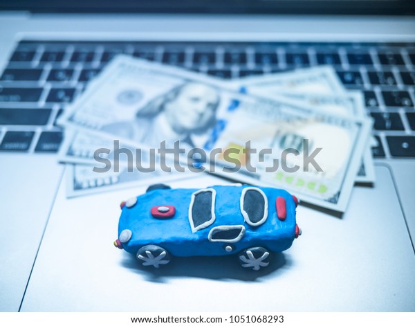 Plasticine toy car with dollars is on the
laptop. The
programmer
