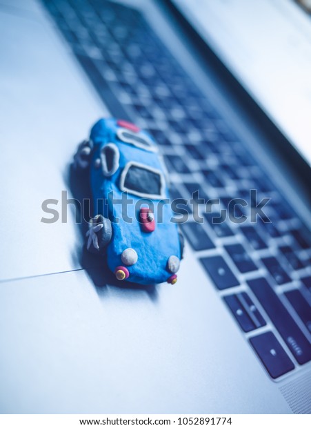 Plasticine toy car with dollars is on the\
laptop. The\
programmer