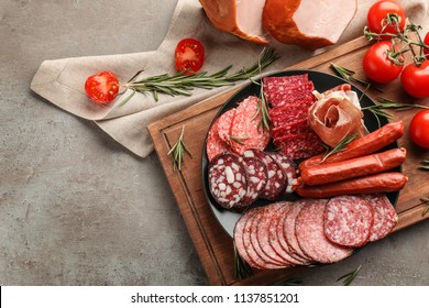 Plate with assortment of delicious deli meats on grey background