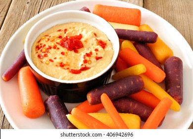 Plate Of Baby Rainbow Carrots With Hummus Dip, Close Up On A Rustic Wooden Background