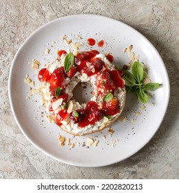 Plate With Bagel With Mascarpone, Strawberries And Basil On The Table