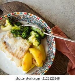 Plate With Baked Cod Fillet With Potatoes And Broccoli On The Table