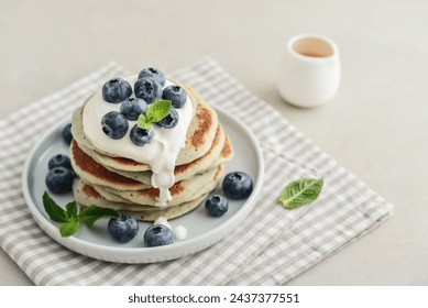 Plate blueberry pancakes with sour cream and coffee out in the background. - Powered by Shutterstock