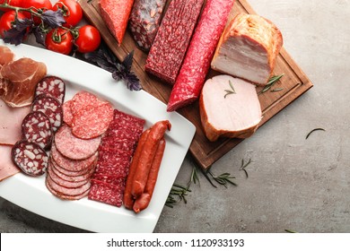 Plate and board with assortment of delicious deli meats on table