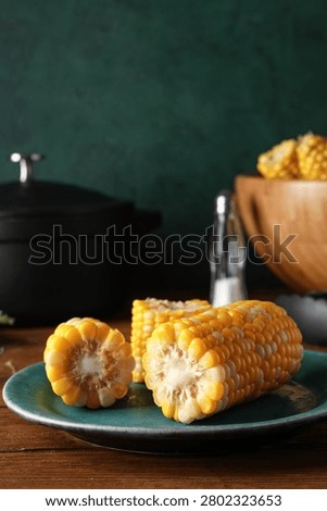 Plate with boiled corn cobs on wooden table