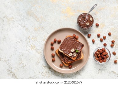 Plate of bread with chocolate paste and hazelnuts on light background - Shutterstock ID 2120681579