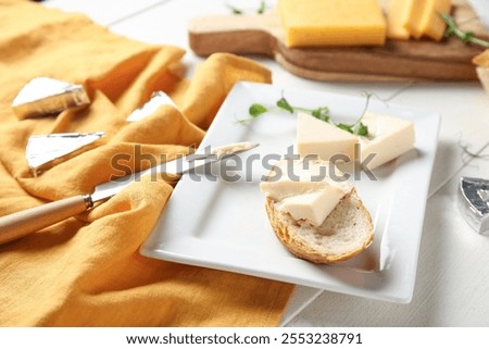 Plate with bread, triangles of tasty processed cheese, micro green and napkin on light wooden table