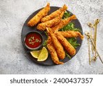 plate of breaded Torpedo shrimps on grey painted kitchen table background, top view