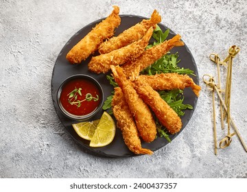 plate of breaded Torpedo shrimps on grey painted kitchen table background, top view