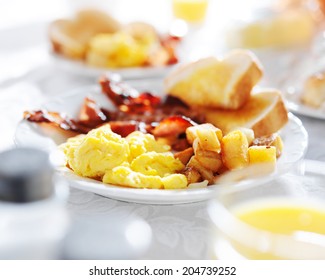 plate of breakfast food with bacon, eggs, toast, and fried potatoes