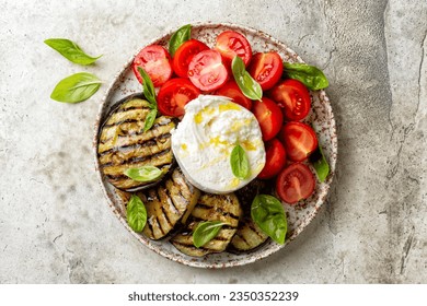 Plate with Burrata or mozzarella cheese and vegetables, grilled eggplant, tomatoes, basils, grissini and olive oil. Italian food, snack. - Powered by Shutterstock