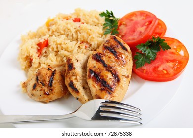 A Plate Of Cajun Chicken And Rice With A Sliced Tomato And A Fork