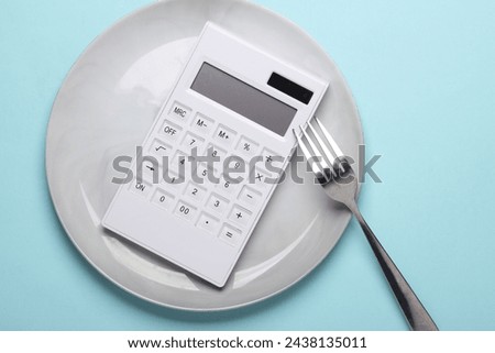 Plate with calculator and fork on a blue background. Reset evening, count calories
