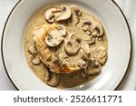 a plate with a chicken meat in cream sauce of mushrooms