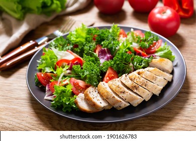 plate of chicken salad with vegetables on wooden table
