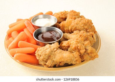 A Plate Of Chicken Wings And Baby Carrots With Ranch Dressing And Barbecue Sauce