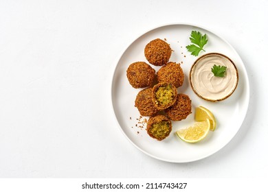Plate of chickpeas falafel with tahini sauce isolated on white background. Top view, copy space