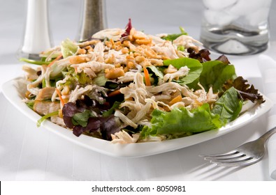 A Plate Of Chinese Chicken Salad Topped With Peanuts