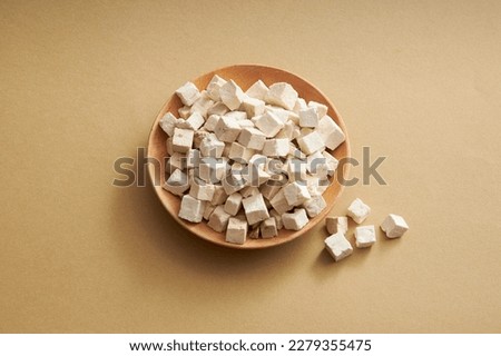 A plate of Chinese medicinal herbs of wolfiporia extensa or poria cocos on round dishes on light brown background. Herb has many effects: anti-oxidant, anti-cancer, anti-viral…