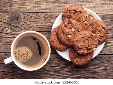 Plate With Chocolate Cookies And Cup Of Hot Coffee On Old Wooden Table. Top View