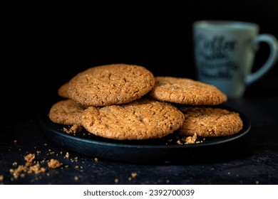 Plate of chocolatechip cookies on a dark background with a cup of coffee