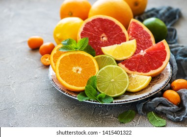 Plate with citrus fresh fruits on a concrete background - Shutterstock ID 1415401322
