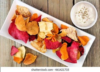 Plate of colorful organic vegetable chips with dip downward view on rustic wood  - Powered by Shutterstock