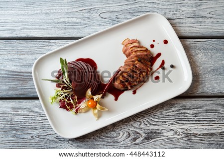 Plate with cooked meat. Sliced meat with decoration. Duck breast with sweet sauce. Delicacy of European cuisine.