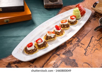 Plate Of Corn Chips Nachos With Fried Minced Meat And Cream Sauce On Old Map Background Side View