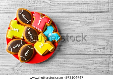 Plate with creative cookies decorated in football style on wooden background